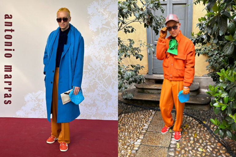 Siniseen takkiin ja oransseihin housuihin pukeutunut mies seisoo Kampaamo Helsingin ulkopuolella, hiukset kiiltävät kuin juuri Kampaapo Annankadun kiiltokäsittelystä.